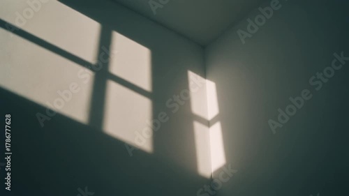 Abstract shadow from a window on a wall corner, forming a geometric shape with contrasting light and dark areas. Minimalist and modern.
