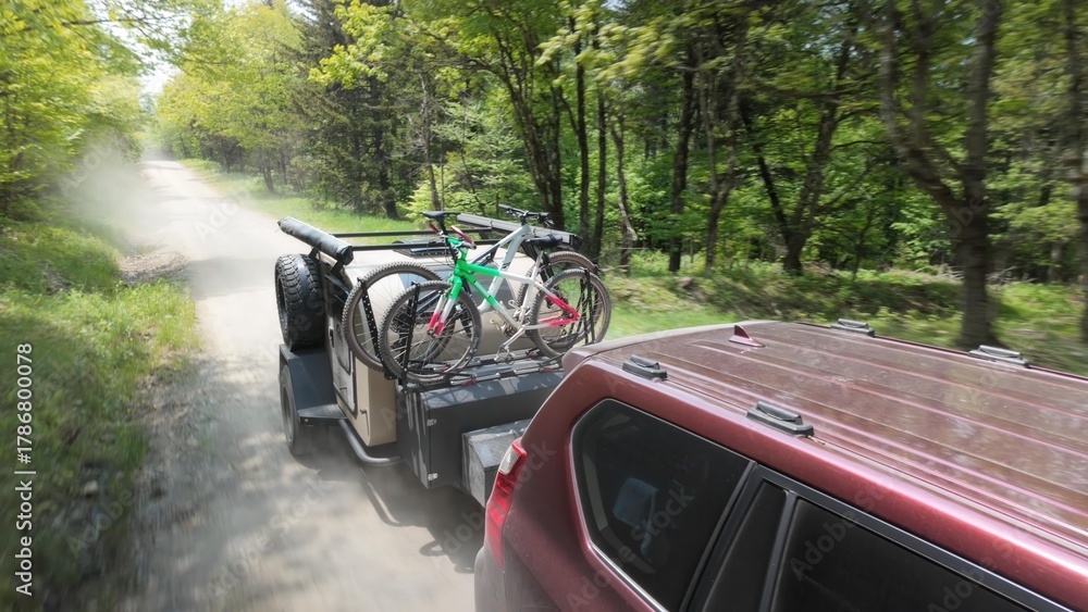 Obraz premium A family enjoys a camping trip in the Appalachian Mountains, towing a teardrop trailer and bicycles through the lush greenery of Dolly Sods.