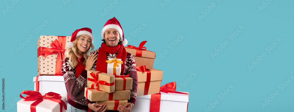 Obraz premium A joyful couple wearing festive sweaters and Santa hats stands among beautifully wrapped gifts. They smile brightly, capturing the spirit of Christmas in a vibrant holiday atmosphere.