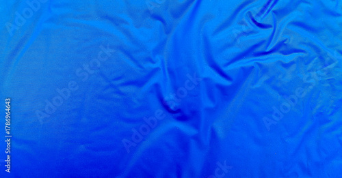 Smooth blue waterproof fabric with light wrinkles and soft reflections, ideal for background, design mockups, or outdoor gear material texture close-up.