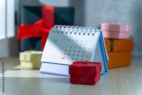 A December desk calendar highlighting Christmas and Boxing Day is surrounded by colorful gift boxes of various sizes, symbolizing holiday sales, planning, and celebrations.