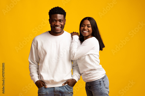 Billede på lærred A young couple stands close, smiling broadly