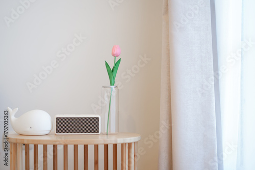 A flower vase, speakers and a doll are placed on a simple wooden table.