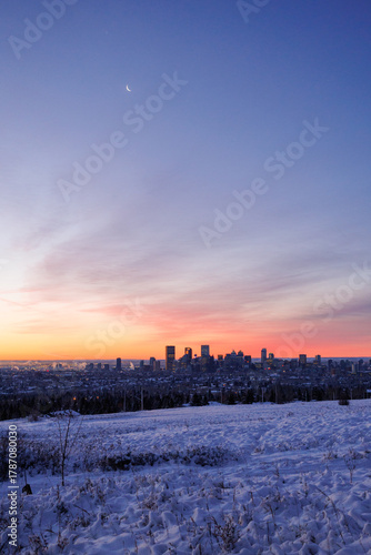 The outline of downtown Calgary at dawn with the moon in the sky