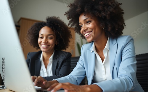 Business team two happy busy diverse young professional executives working together on computer at work. Manager consulting employee using laptop talking on financial project management in office.