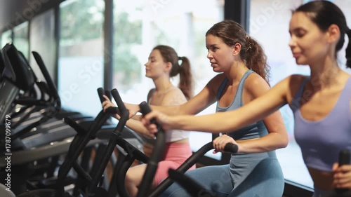 Woman holds the handles and pedals on an air bike, she performs a fat-burning workout against the clock. Athletic women in the gym. High quality 4k footage