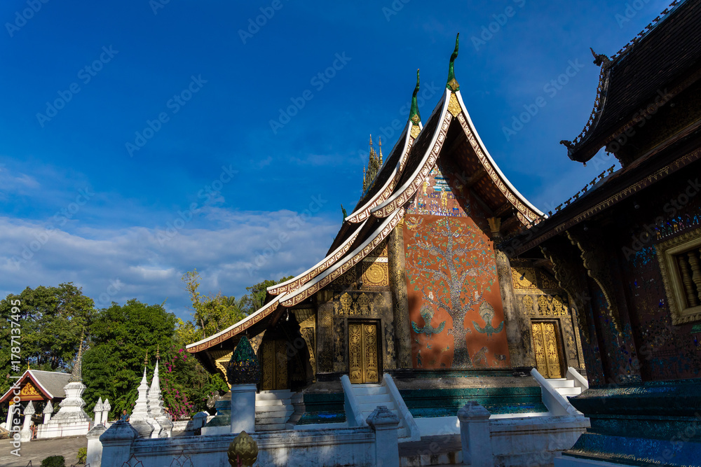 Fototapeta premium An important Buddhist monastery and symbol of the UNESCO World Heritage town of Luang Prabang, featuring the distinctive low-sweeping tiered roofs.