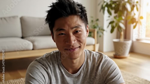 Happy young Asian man smiling looking at camera during video conference call at home.