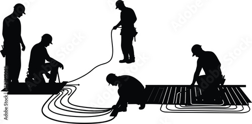 Construction workers installing underfloor heating system, laying heating pipes and cables, professional plumbing and radiant floor installation at construction site