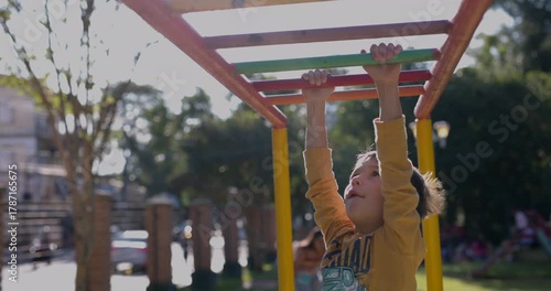 Young boy making his way across the monkey bars in park