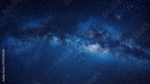 Panoramic blue night sky with the Milky Way, stars and nebula across a dark horizon