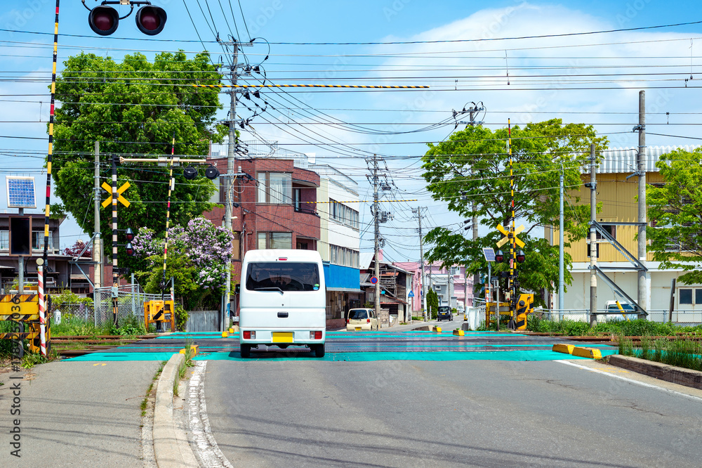 Obraz premium 住宅地の踏切を通過する自動車