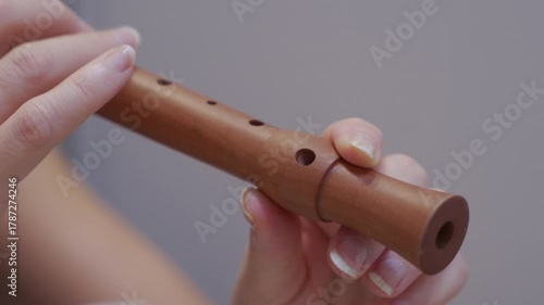 A brown wooden flute is held and played. The fingers cover and uncover the holes, producing a drawn-out sound of varying pitch.
