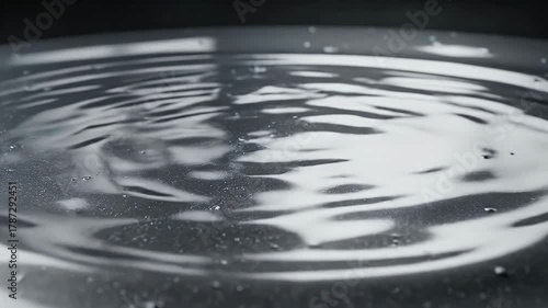 Metallic silver liquid surface with ripples and water droplets