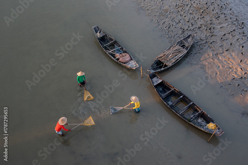 Top view of three unidentified men using fishing nets in shallow water