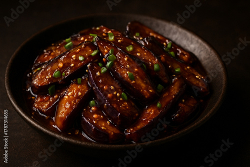 Spicy Chinese-Style Braised Eggplant in Savory Garlic Sauce Garnished with Spring Onions in a Rustic Bowl