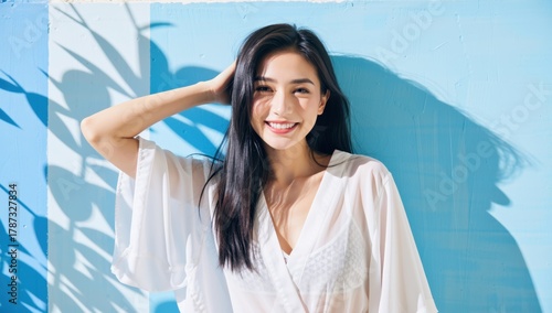Portrait of a beautiful smiling asian woman in a white dress against a blue background with shadows