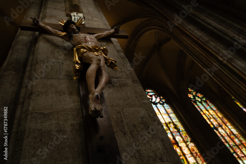 Kutná Hora, Czech Republic – August 8, 2025: Dramatic perspective of Jesus Christ sculpture on the cross with ornate gold leaf details and stained glass windows, Saint Barbara’s Cathedral, Kutná Hora