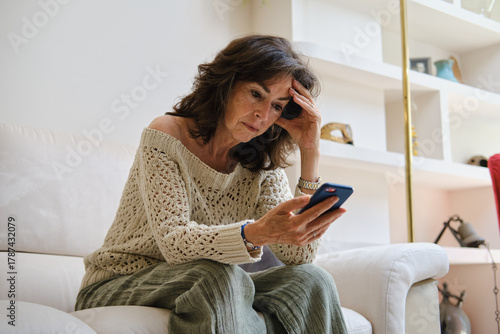Fotografija front view of Senior woman receiving bad news on smartphone feeling stressed