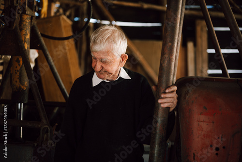 Elderly man in black sweater standing in a rustic barn