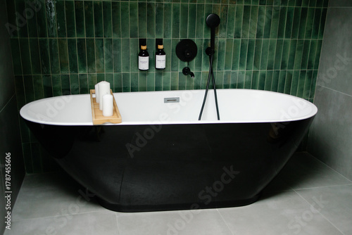 Valokuva Modern bathroom featuring black freestanding bathtub and emerald green tiles