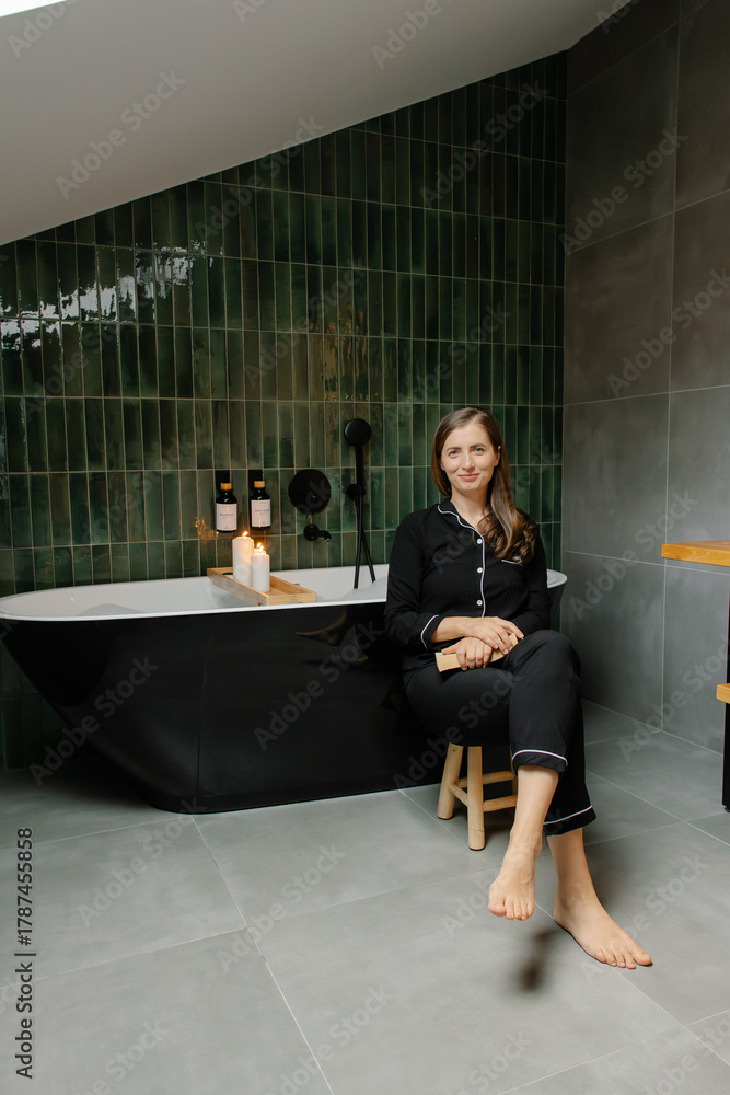 Fototapeta premium Woman in pajamas sitting in modern luxury bathroom