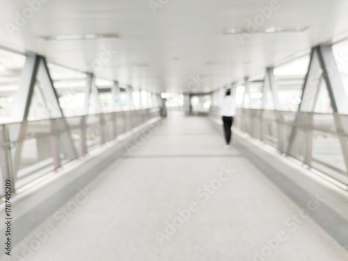 blurry background crowd anonymous walking on sky walk way in city with people walking into entrance.