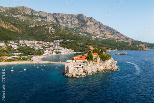 Aerial view of the red-roofed buildings of Sveti Stefan jutting into the turquoise Adriatic, a jewel amidst the rugged Montenegrin coastline, Sveti Stefan, Budva Municipality, Montenegro.
