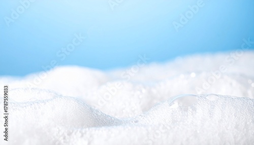 Close-up of fluffy white soap bubbles on a bright blue background clean texture