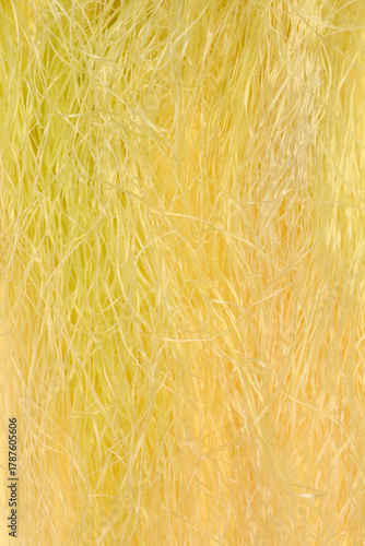 An extreme vertical close-up of fine, soft, light yellow corn silk fibers tangled together, filling the frame against a muted yellow background