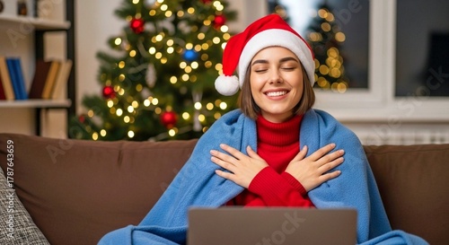 Joyful Woman in Santa Hat Relaxing with Laptop by Christmas Tree – Cozy Holiday Home Scene