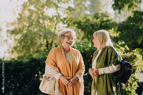 Принти на полотні Two senior women sharing a laugh outdoors in autumn sunlight