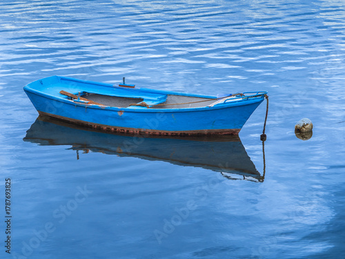 Barca azul en el agua del mar en calma amarrada
