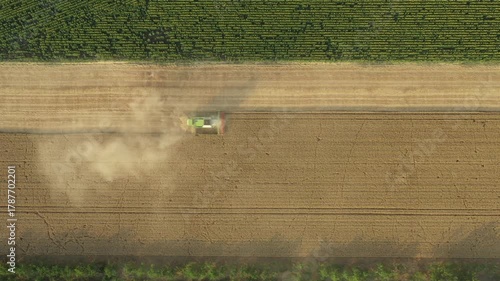Above top view, dolly move overfly agricultural harvester, combine as he cutting and harvesting mature wheat on farmland. Harvest time in summer, season. 