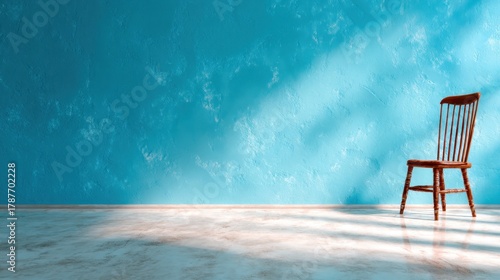 This image features a striking turquoise wall with a single wooden chair, creating a sense of solitude and simplicity in a minimalist setting that emphasizes calmness.