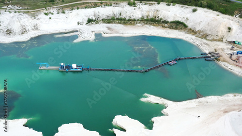 Aerial view of an industrial dredge extracting quartz sand from a brilliant turquoise lake in a mineral quarry