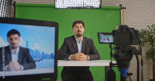 Wallpaper Mural A live streaming studio setup with a camera, monitor, and green screen, showcasing a professional environment. A man in a suit presents information or news. Ideal for media production. Torontodigital.ca