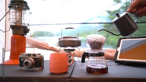 Coffee drip set for camping inside a tent, looking out to the mountain and lake view.