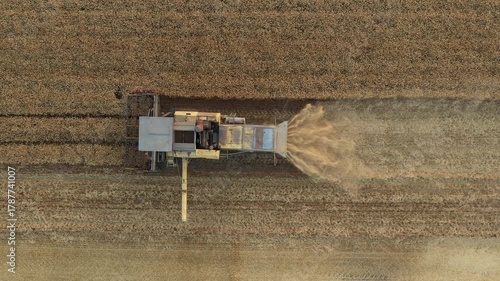Above top view, dolly move follow over agricultural harvester, combine as he cutting and harvesting mature wheat on farm fields. Harvest time in summer, season.