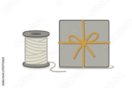 Square gift package tied with yellow ribbon and twine spool