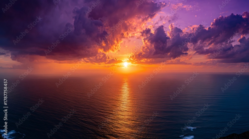 Fototapeta premium Vibrant sunset over ocean horizon creating a dramatic colorful sky with dark clouds and shining water