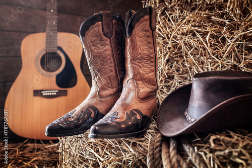 Cowboy hat guitar and boots in barn, country music festival live concert or rodeo background