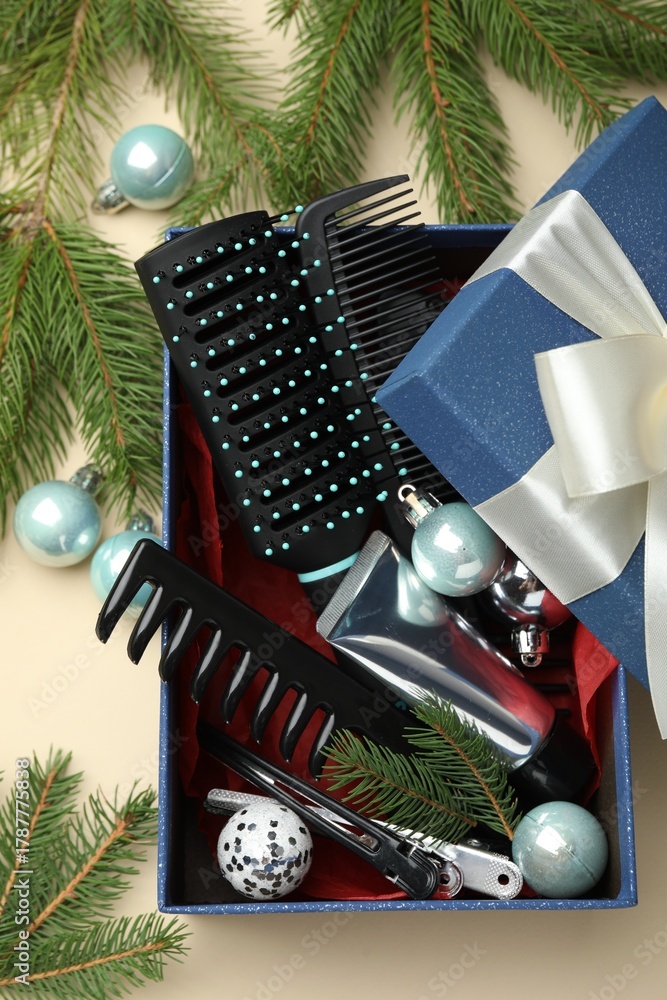 Obraz premium Hairdresser's tools in gift box and Christmas decor on beige background, flat lay