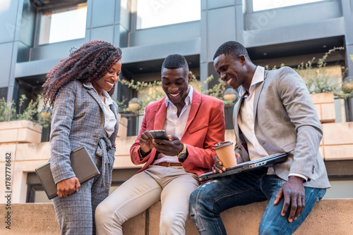 Group of multiracial business people using mobile phone outdoors and smiling