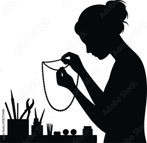 silhouette of jewelry maker assembling necklace on workbench