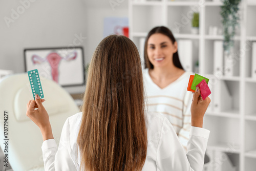 Female gynecologist with contraceptive pills and condoms in clinic, back view