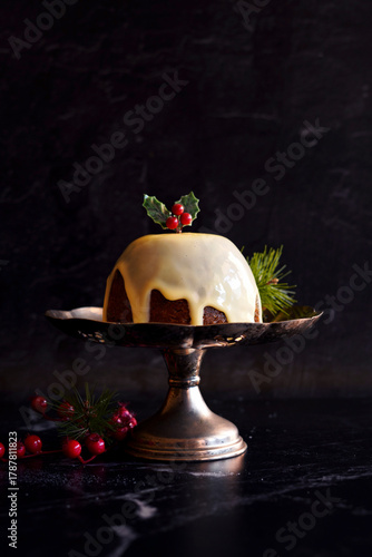 English style festive Christmas plum pudding dessert, served with traditional brandy custard, against black marble background.