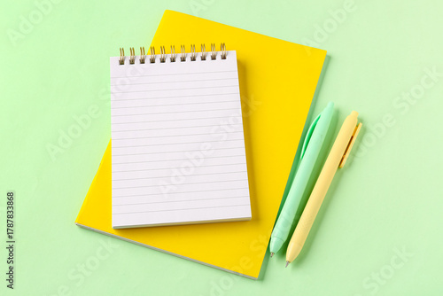 School notebooks and pens on green background
