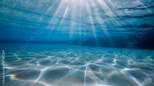 Fototapeta Naklejka Na Ścianę i Meble -  Underwater sunbeams pierce clear blue ocean water onto sandy seabed image