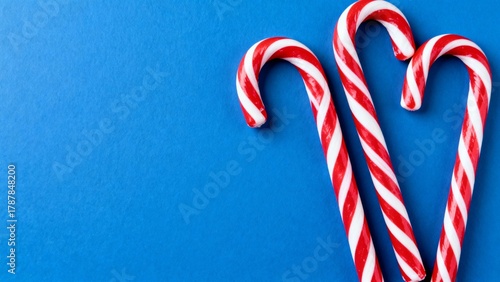 Christmas background. Red and white candy canes with blue copy space. Flat lay new year minimal.